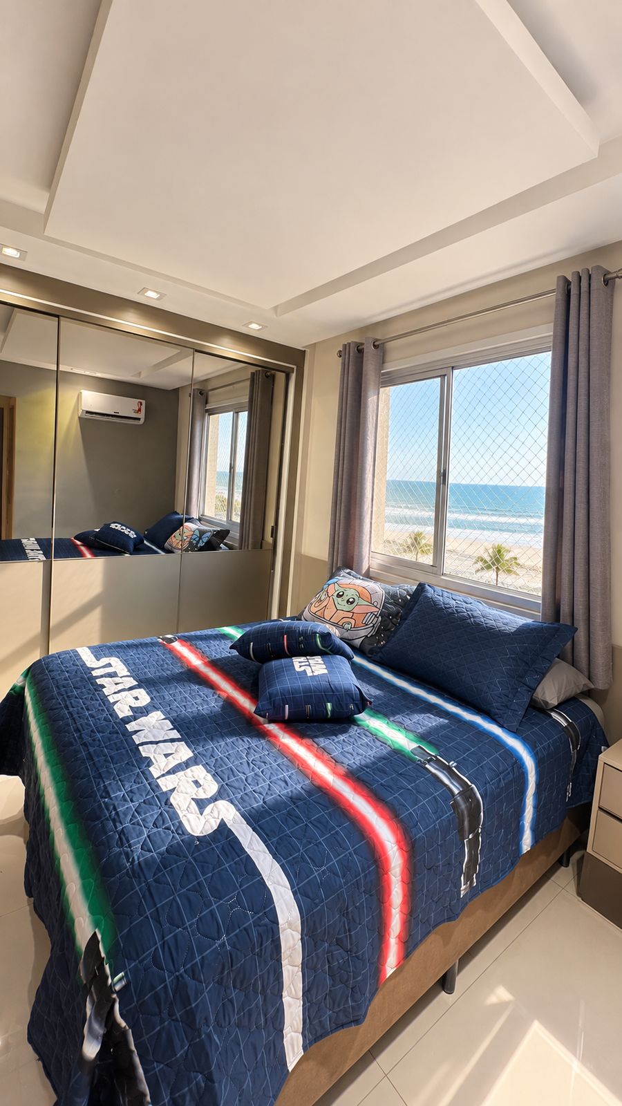 Suíte real do Maré com cama de casal, armário espelhado e vista para o mar.